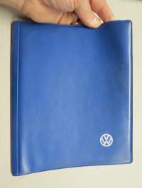Volkswagen -kansio ohjekirjalle ja muille papereille, VW-logo painettuna kannessa